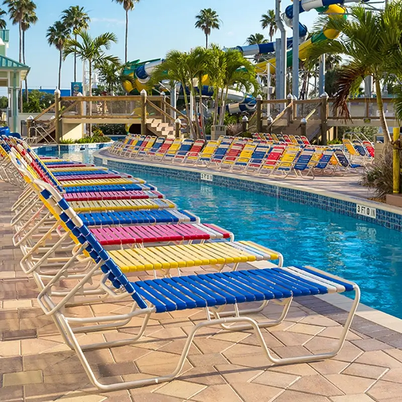 Commercial waterpark featuring rows of colorful strap chaise lounges surrounding a swimming pool and waterslide complex.